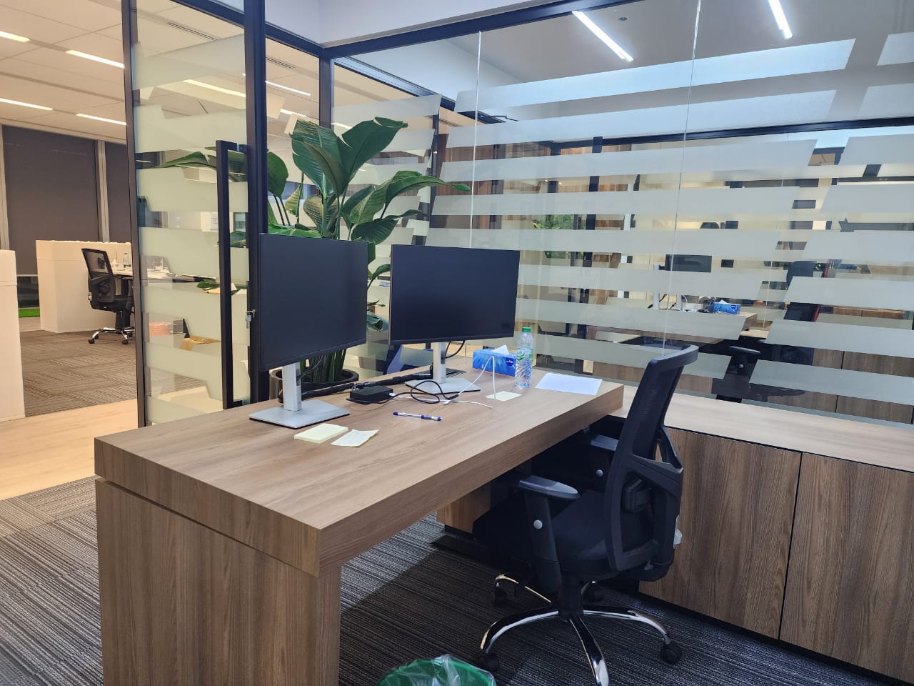 Workers cubical with glass walls and a wooden workstation